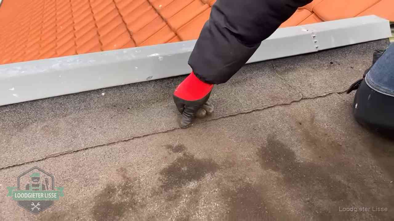 Lekkage bij de naad van een plat dak in Lisse Vakman wijst een naad met vochtplekken aan op een bitumen plat dak in Lisse