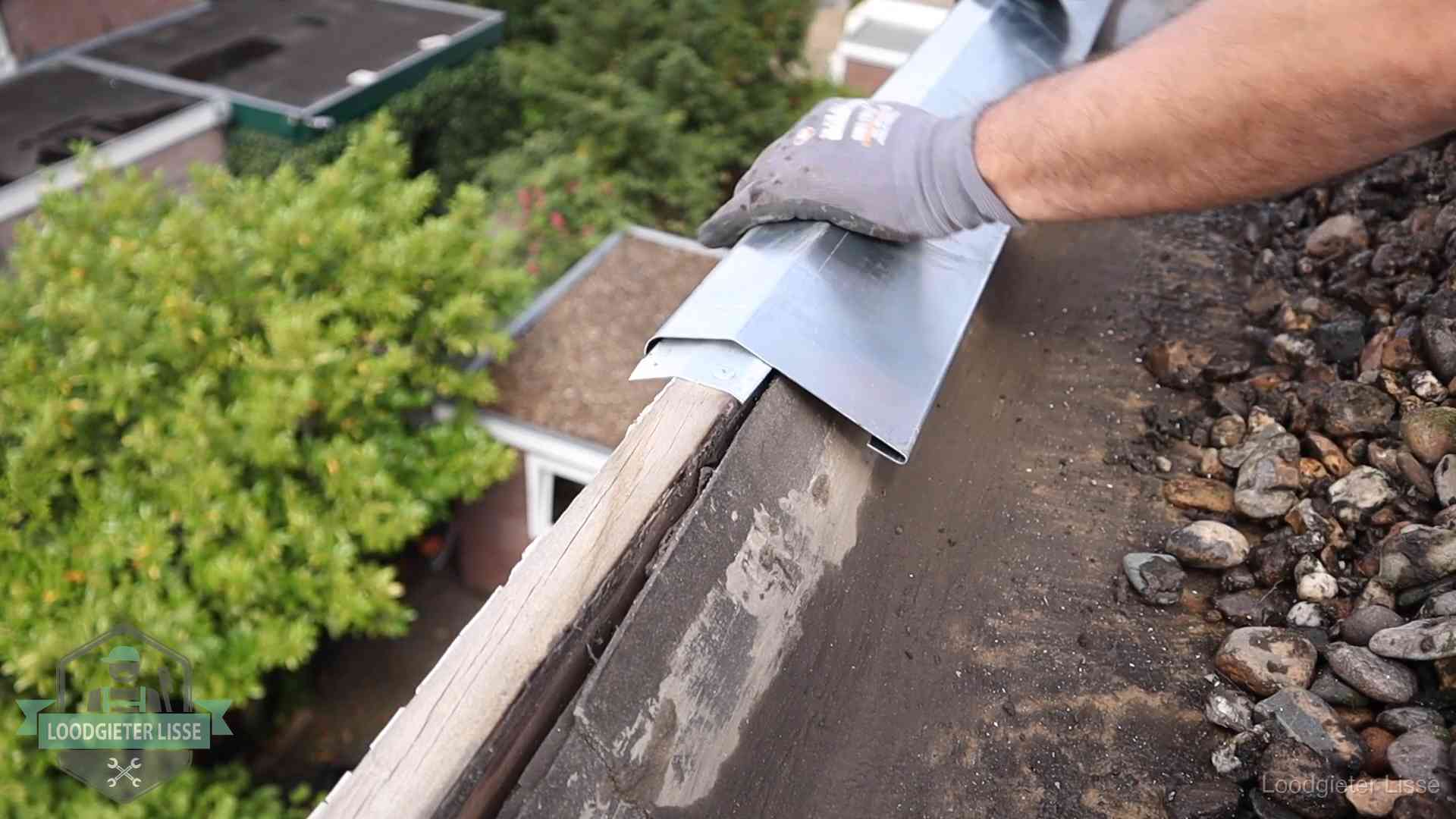 Daklekkage per wijk in Lisse Dakdekker plaatst een zinken deklijst op een dakrand met uitzicht over een woonwijk in Lisse