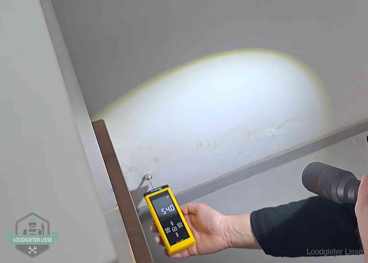 Vochtmeter tegen een natte wand met lekkagesporen in Lisse