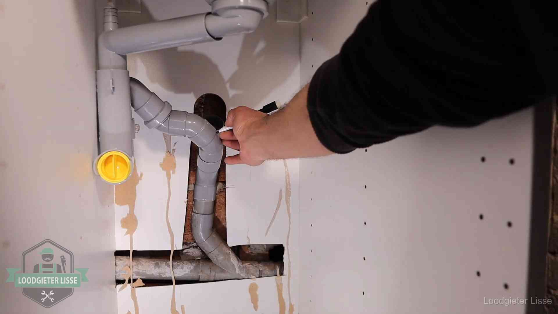 Loodgieter voor verhuurders en bedrijven in Lisse Loodgieter markeert een pvc-afvoerbuis onder een gootsteen in Lisse