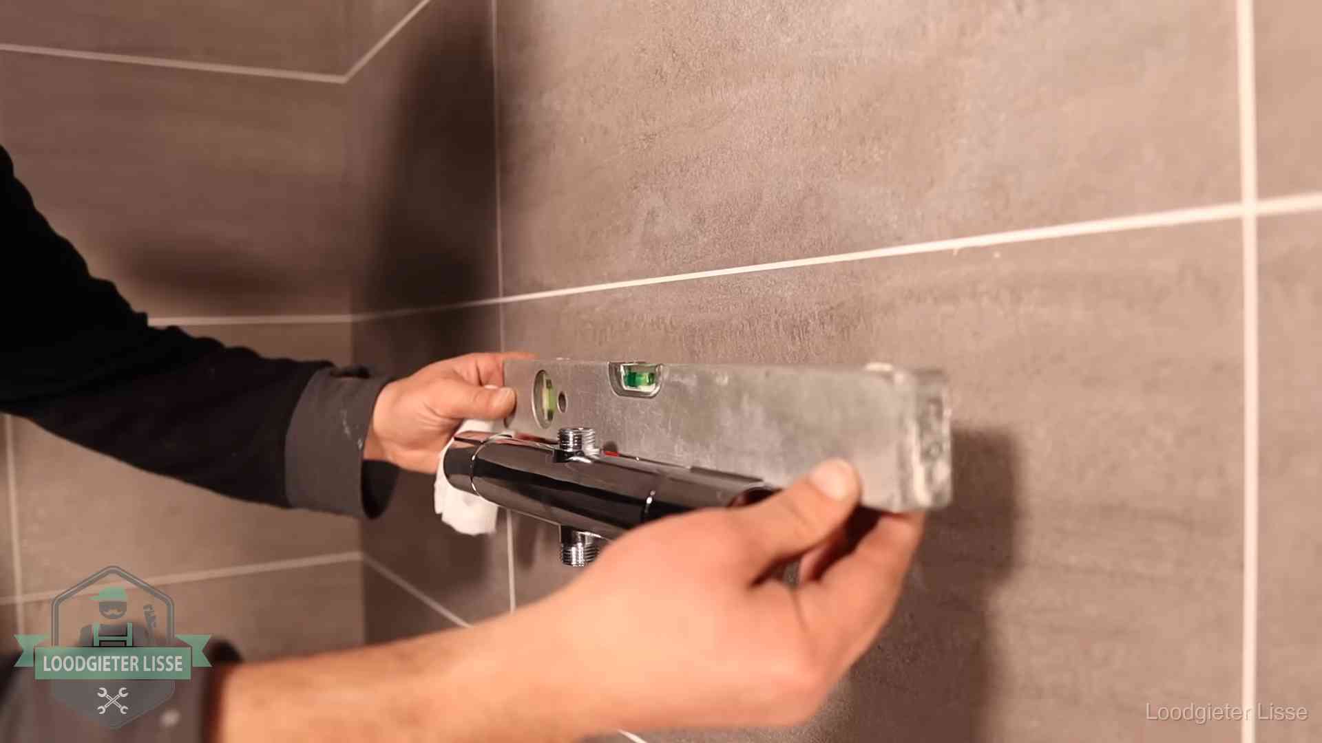 Loodgietersbedrijf voor sanitair in Lisse Loodgieter lijnt een douchekraan uit met een waterpas in een woning in Lisse