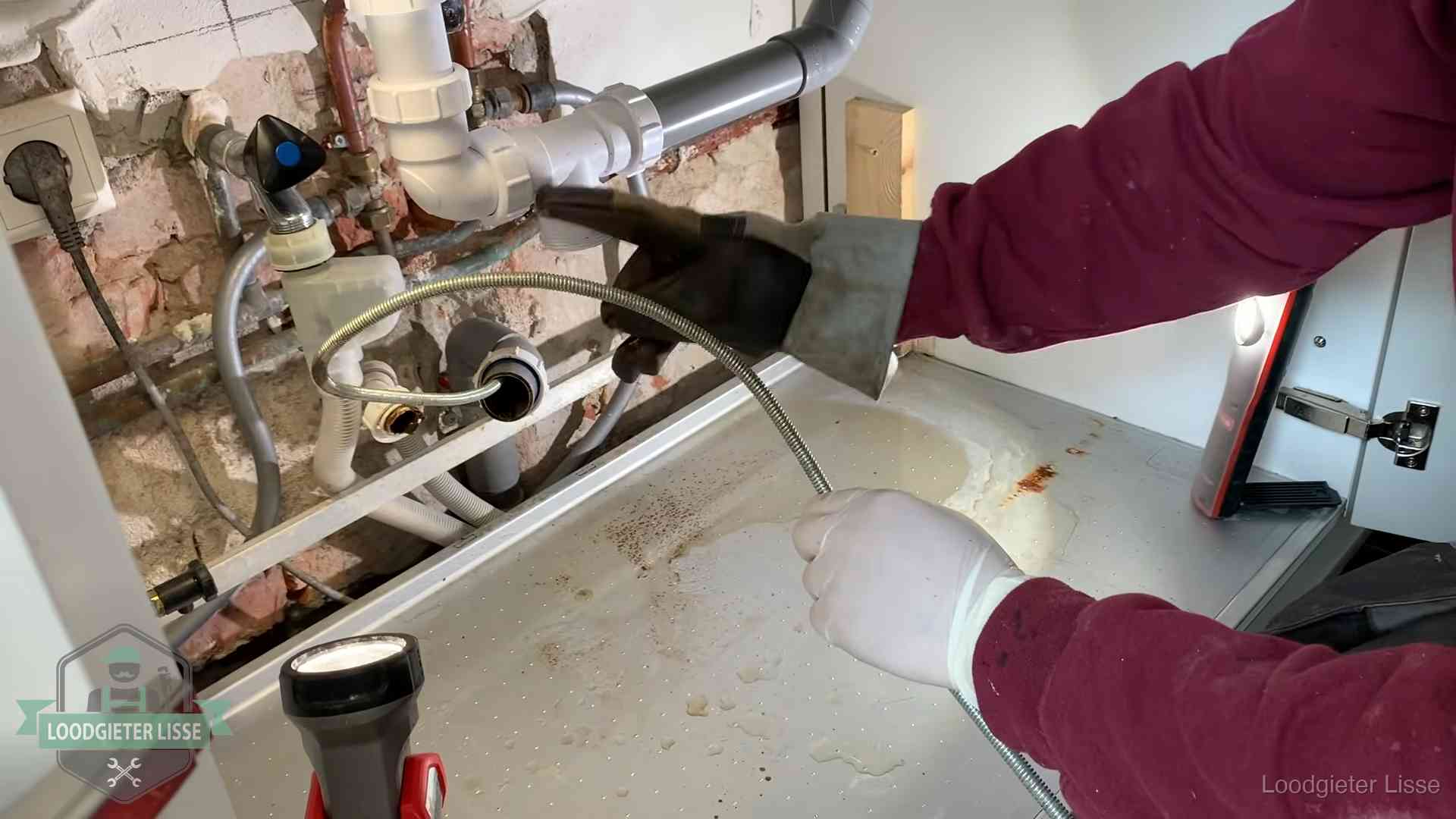 Spiraal of hogedruk in Lisse Ontstoppingsveer gaat in een geopende sifonaansluiting onder het aanrecht in Lisse