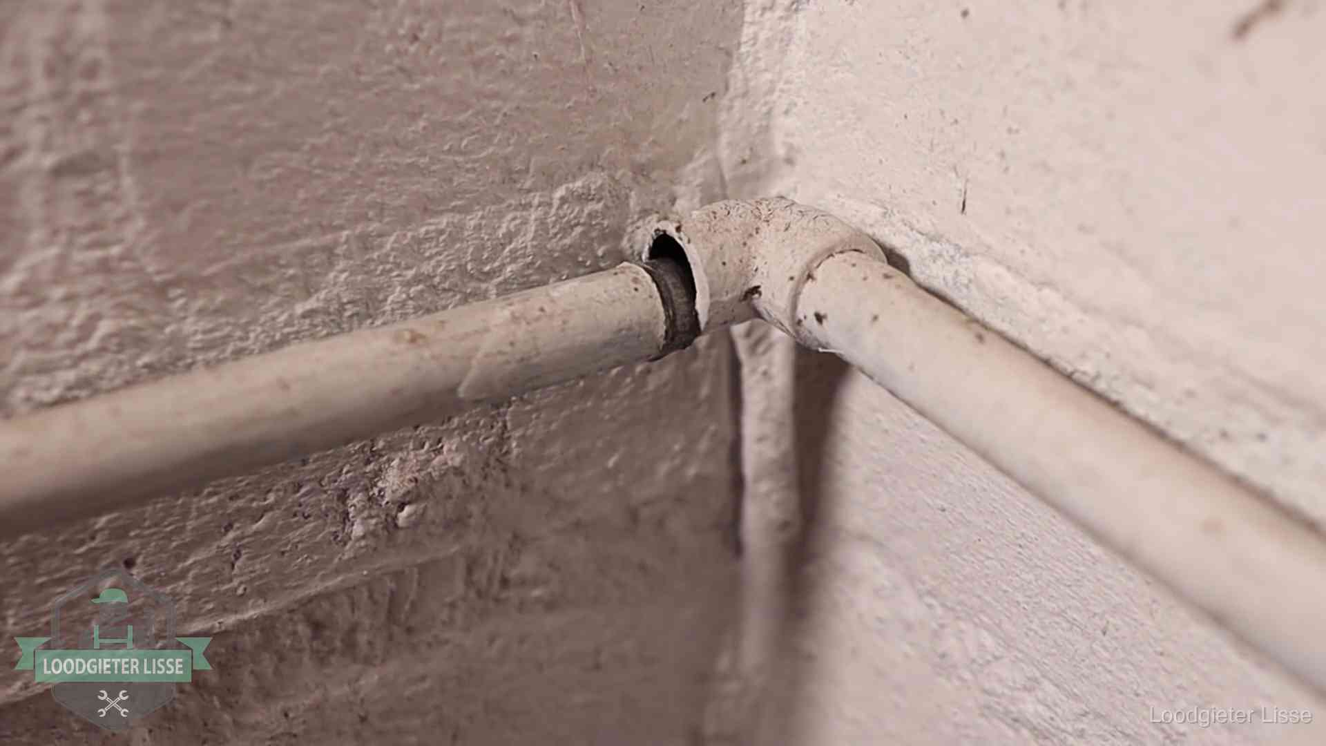 Oude geverfde waterleiding met een losliggende fitting in een woning in Lisse